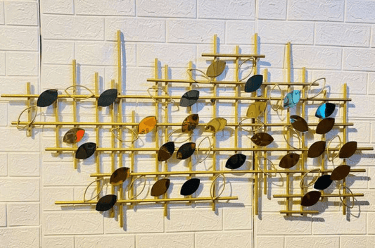 Decorative wall art with gold frame and multicolored leaves on a white tiled wall.