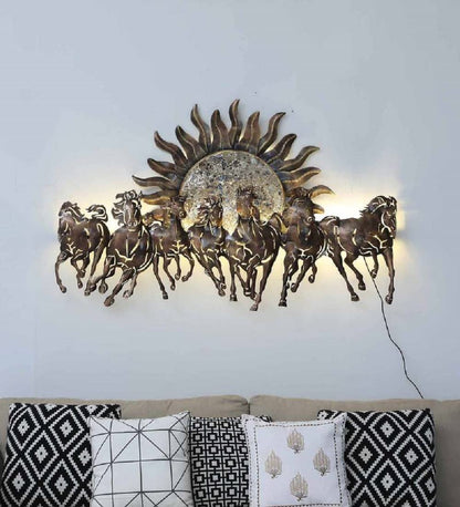 Decorative wall art with horses and a sun design on a light gray wall above a sofa.