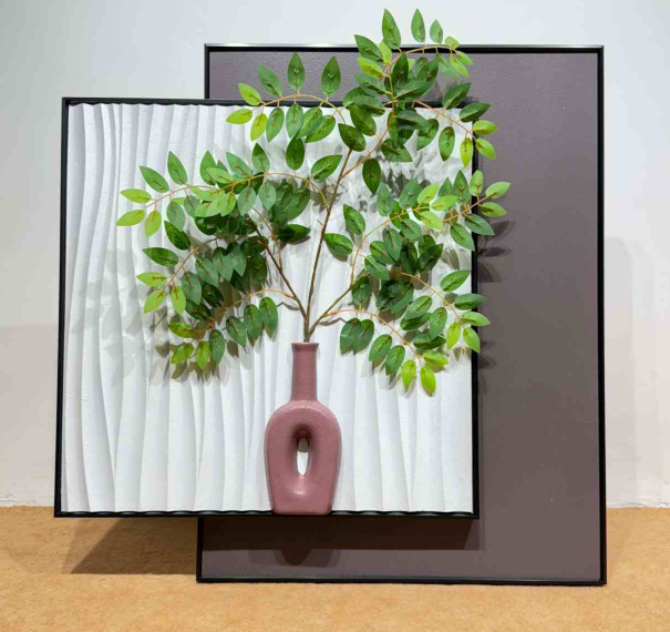 Framed artwork of a vase with green leaves against a textured white background