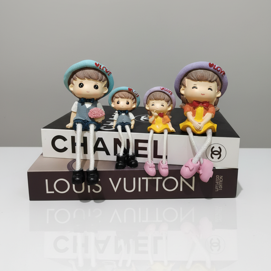 Four children figurines on top of a Chanel and Louis Vuitton box