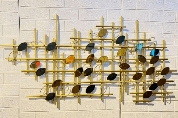 Decorative wall art with gold frame and multicolored leaves on a white tiled wall.