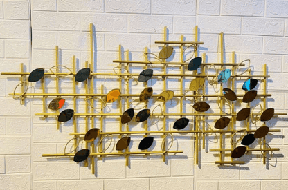 Decorative wall art with gold frame and multicolored leaves on a white tiled wall.